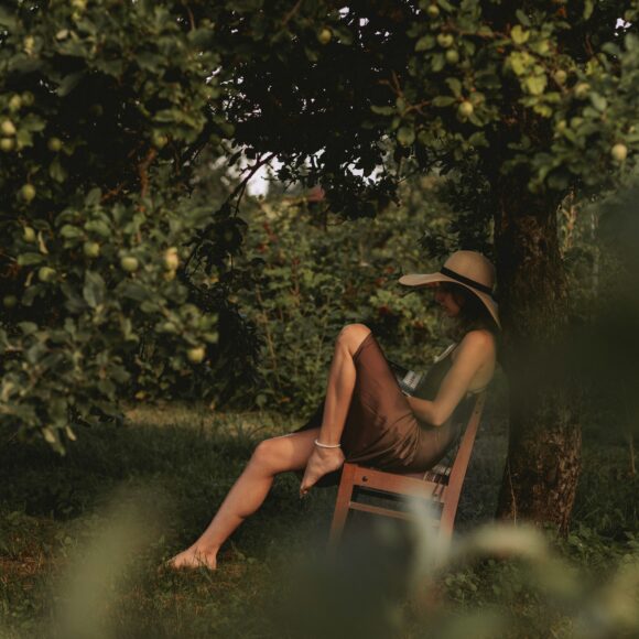 A woman sitting in a chair under a tree